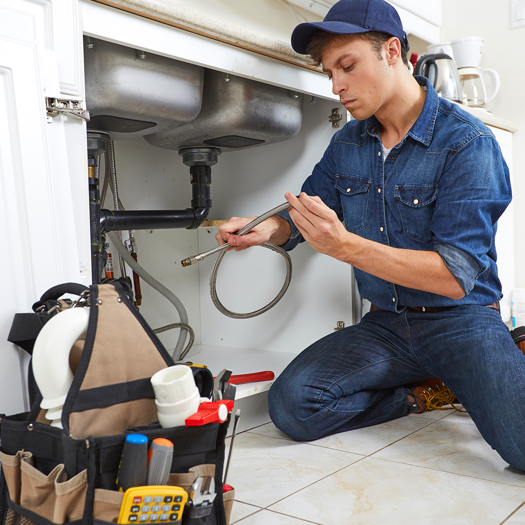 man working under a kitchen sink